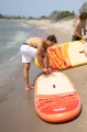 paddler zakłada leash na kostkę przy pomarańczowej desce SUP Aqua Marina Monster na plaży-Monster
