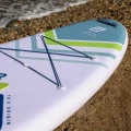 deska sup Gladiator Origin 10.6 – detal dziobu na kamienistej plaży, elastyczne linki bagażowe i uchwyt do przenoszenia