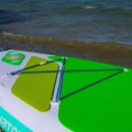 sup Gladiator Origin 10.8 SC – tylny bagażnik z linkami, zielony pad EVA, ujęcie deski przy brzegu i falach
