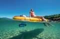 kobieta odpoczywająca na desce SUP Aqua Marina Fusion z zamontowanym silnikiem podwodnym na krystalicznie czystej wodzie