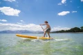 mężczyzna na desce SUP Aqua Marina Fusion przyspieszający na fali blisko plaży
