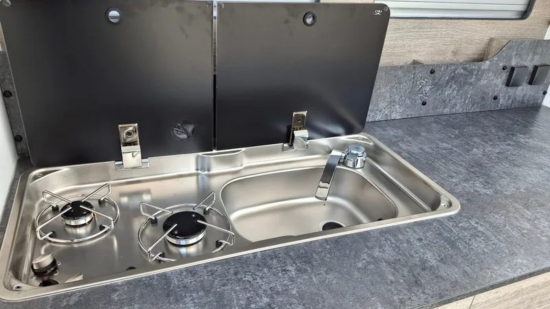 Bushcamp Explorer – kuchnia w tylnej klapie: zlew i kuchenka 2-palnikowa ze szklaną pokrywą